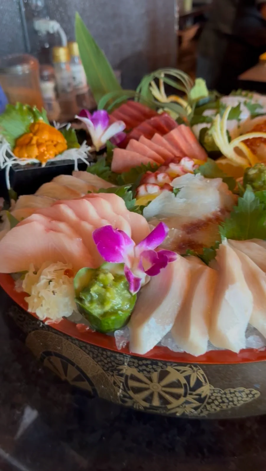 Sashimi platter of yellowtail, tuna, white fish, sweet shrimp and uni, garnished with orchids, shiso and carved lemon