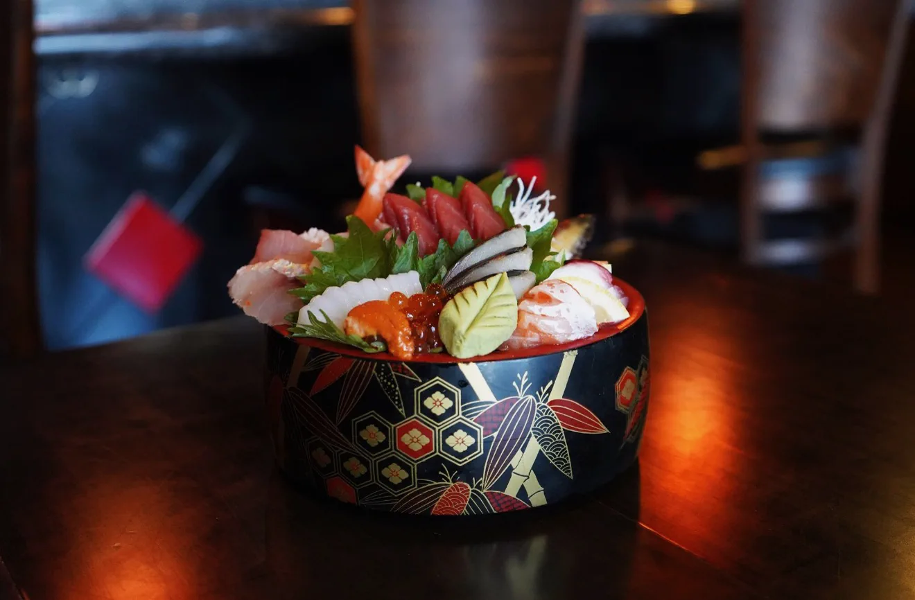 Signature chirashi bowl topped with tuna, shrimp, squid, mackerel, uni and ikura in a lacquered bowl